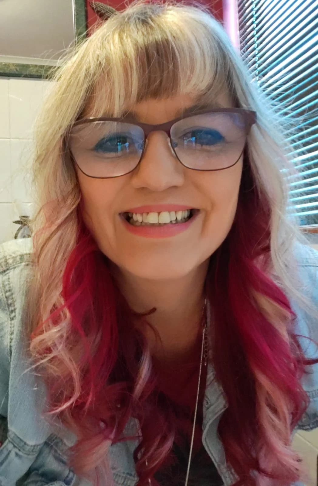 Lisa Snyman, smiling, with glasses and pink-tipped blonde hair
