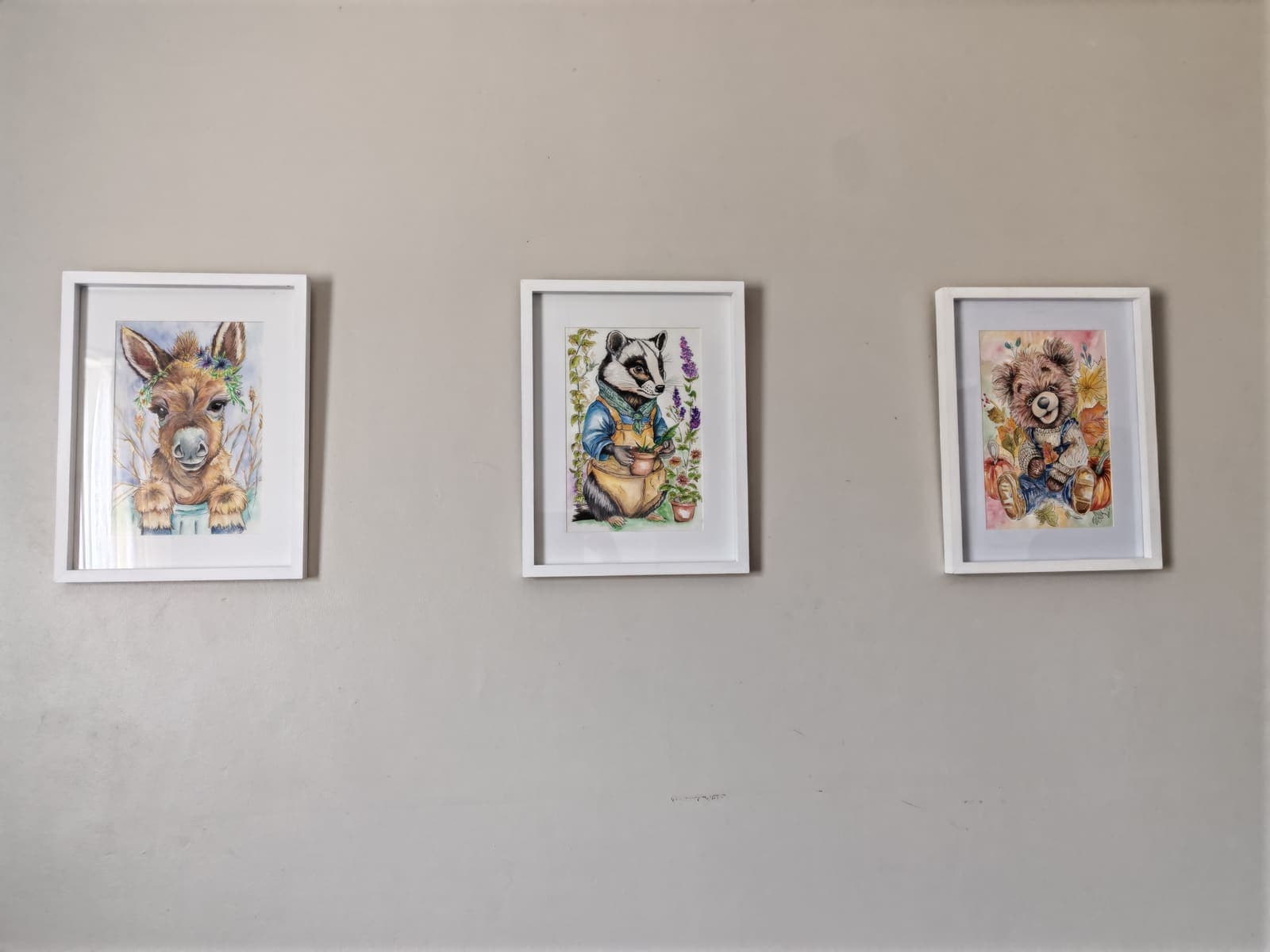 Three framed paintings on a nursery wall