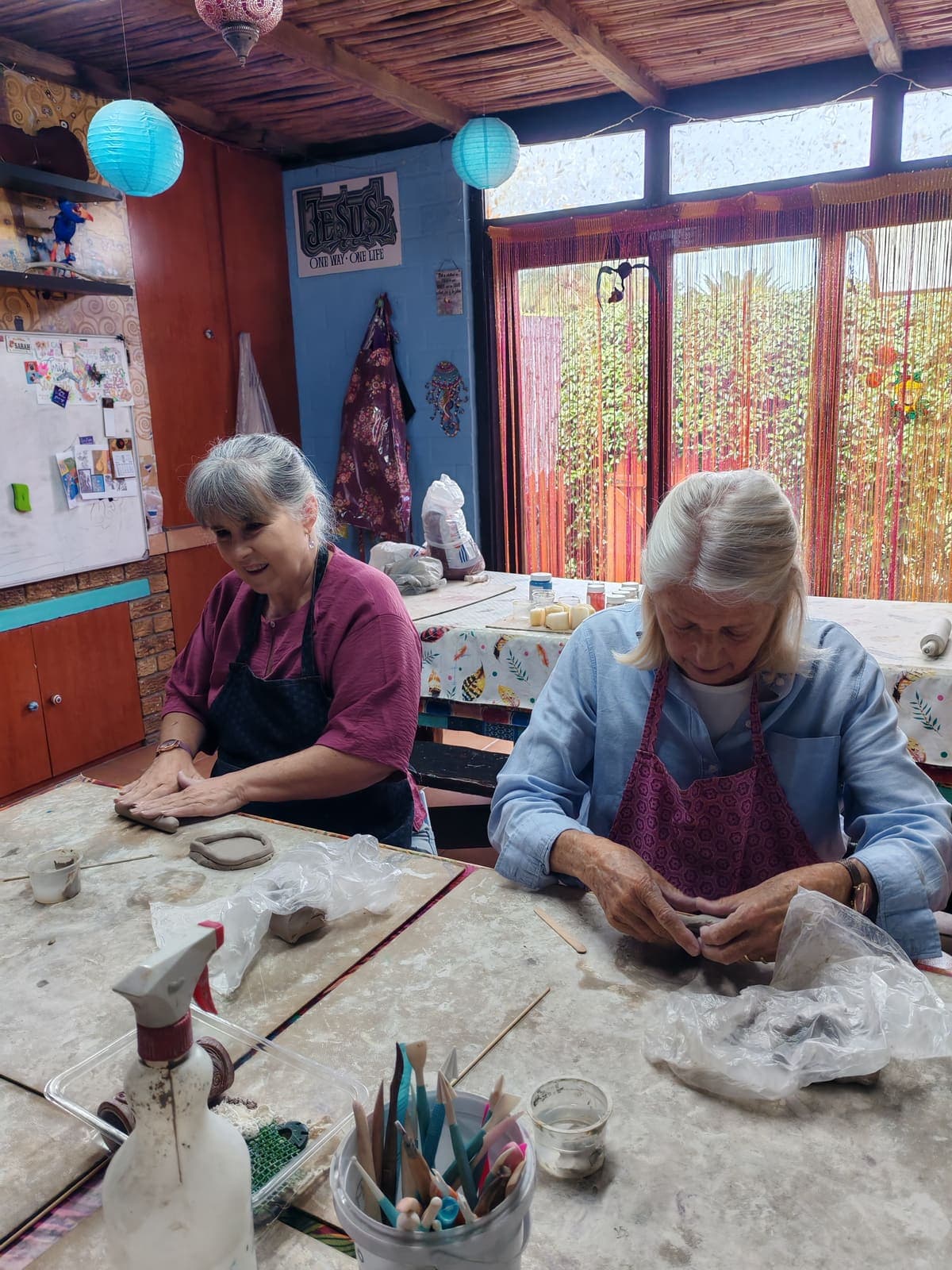 Two women shaping clay at the table